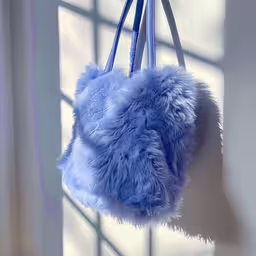 a fluffy purse hanging from a small blue hook,a blue bag hanging from a rope by a window
