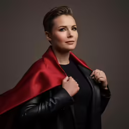 a woman wearing a black jacket and red cape