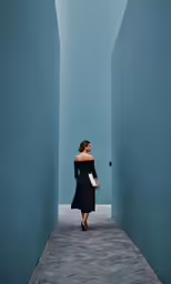a woman in a black dress walking down a narrow street