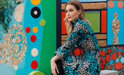 a woman posing near colorfully painted wall