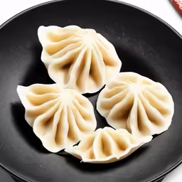four dim dumplings being cooked in a black wok