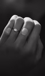 a woman with a ring on her left hand holding a ring on her right finger
