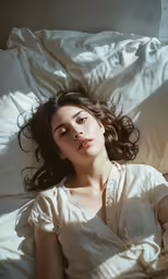 a woman with long hair laying on a bed