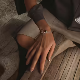 a woman is showing off her silver wrist chain