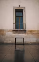 a bench sitting on the side of a building in front of a window