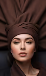 a woman wearing brown is looking into the distance