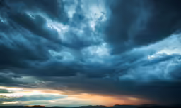 storm clouds and sun peaking through the dark clouds over the ocean