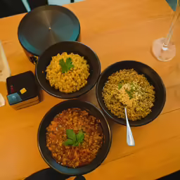 four black bowls on top of a wooden table