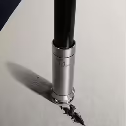 a metal object with black top next to a shadow