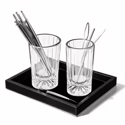 two glasses with silver straws sitting on a black tray