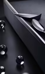 two silver spoons are next to a black drawer