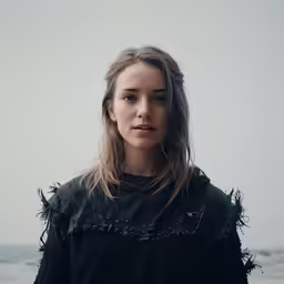 a girl is standing on a beach by the water