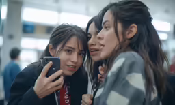 three young girls pose for a photo in an airport
