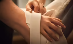a close - up of a person wearing ring on their fingers with a white fabric