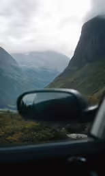 a rear view mirror on the side of a car in the mountains
