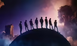 silhouettes of people standing on a huge planet in the sky