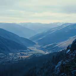 a scenic view of a mountain valley below it with small village nestled in the mountains