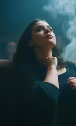 woman sitting down in front of smoke in the dark