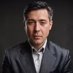 a man with a suit jacket and tie posing for a photo