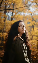 young woman standing in the autumn forest near yellow leaves