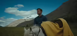 a man wearing a blue shirt is riding on a white horse