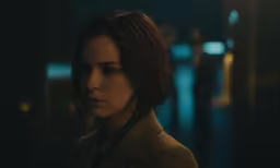 a young lady standing alone in the dark with an intense look