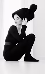 woman wearing black clothes kneeling down with a hat