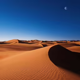 a desert with sand dunes and a moon