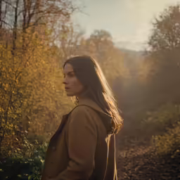a woman is posing near many trees in the woods