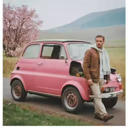 a man standing next to his small car in a rural country