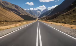 a long straight road running through a mountain landscape