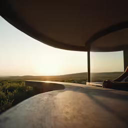 the sun is setting over a hill top near the mountains