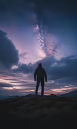 a person standing on top of a hill under the night sky