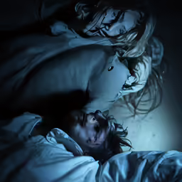 two people are lying in bed at night