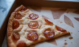 a slice of pizza is sitting on a piece of cardboard