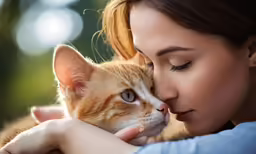 a young woman hugs a cat outdoors with an affection