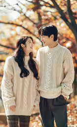 the man and woman are smiling as they stand next to each other,a man and woman are smiling in the fall leaves
