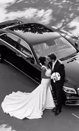 the bride and groom kiss by their parked mercedes