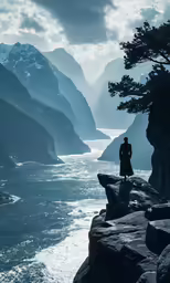 person standing on the edge of a rocky cliff overlooking a body of water with mountains in the background