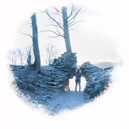 an old photo of a woman standing by a rock wall