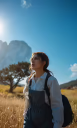 a girl in overalls stands in tall grass