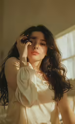 a beautiful woman wearing white looking down holding her head to the side