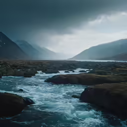 a man stands in front of a river with small boulders