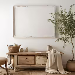 a wooden table topped with a plant next to a white framed picture