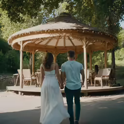 two people are walking through a gazebo with some chairs
