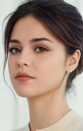 a woman wearing a beige blouse looks at the camera