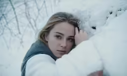 a woman in snow jacket leaning up against wall