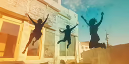 three people leaping on the air in front of a building